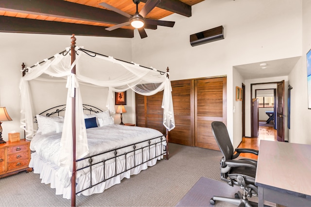 carpeted bedroom featuring lofted ceiling with beams, wood ceiling, a closet, and ceiling fan