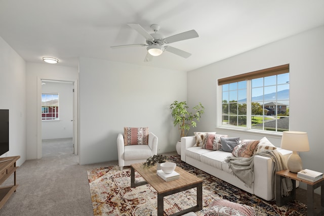 carpeted living room with a mountain view, a wealth of natural light, and ceiling fan