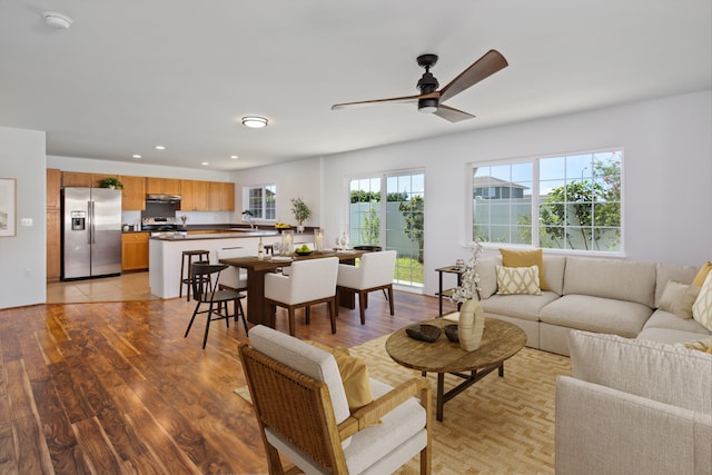 living room featuring ceiling fan, sink, and light hardwood / wood-style floors