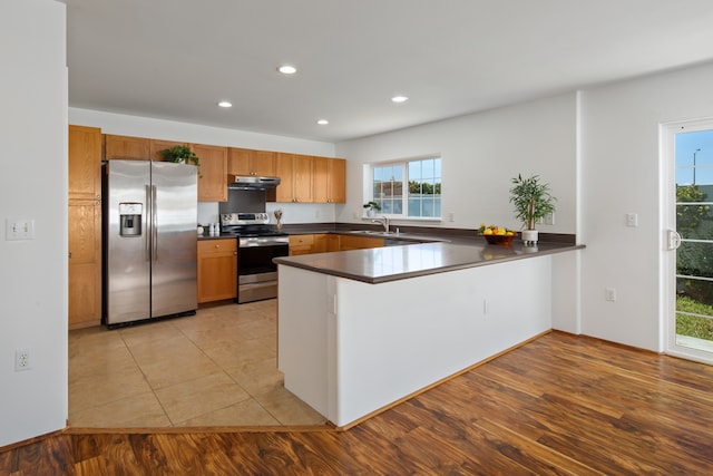 kitchen featuring kitchen peninsula, sink, light hardwood / wood-style floors, and appliances with stainless steel finishes