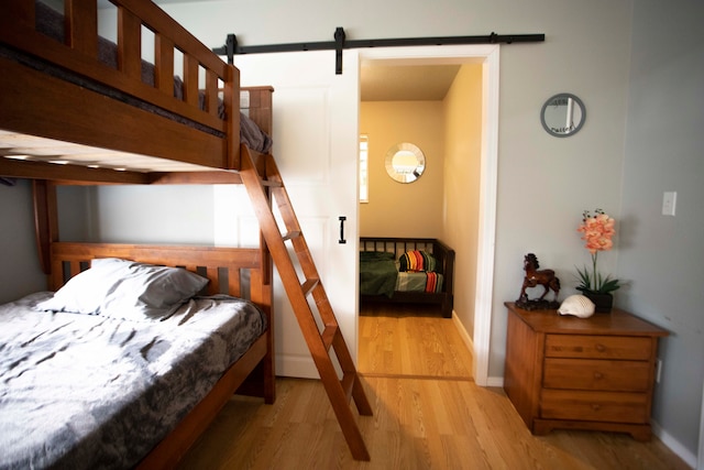 bedroom with a barn door and light hardwood / wood-style flooring