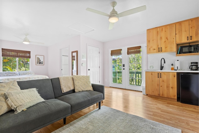 living room with ceiling fan, sink, and light hardwood / wood-style flooring