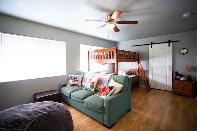 bedroom featuring a barn door, hardwood / wood-style flooring, and ceiling fan