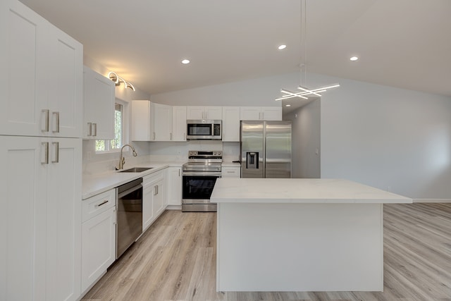 kitchen featuring stainless steel appliances, decorative light fixtures, lofted ceiling, a center island, and white cabinets