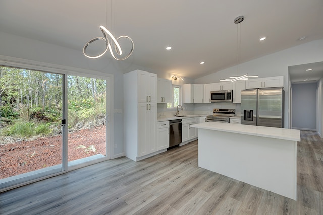 kitchen featuring pendant lighting, stainless steel appliances, vaulted ceiling, and plenty of natural light