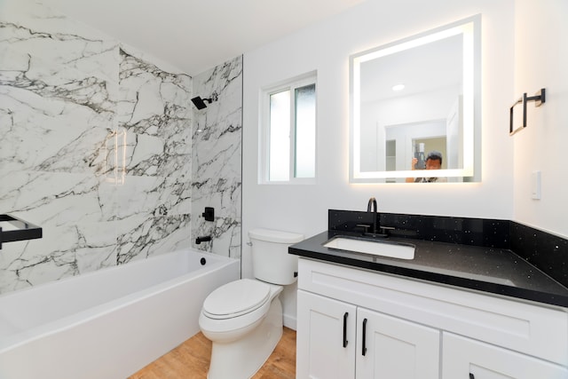 full bathroom with tiled shower / bath, vanity, hardwood / wood-style flooring, and toilet