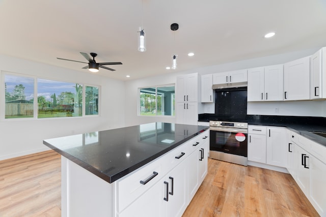 kitchen with white cabinets, hanging light fixtures, a kitchen island, stainless steel electric range oven, and light hardwood / wood-style floors