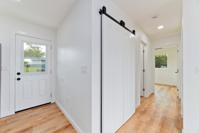 corridor with light hardwood / wood-style flooring and a barn door