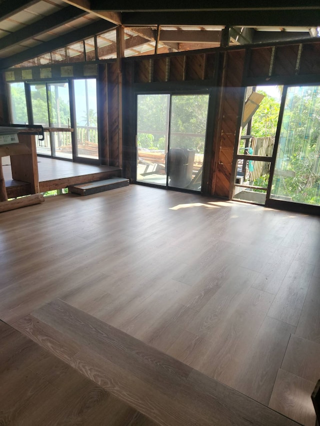 unfurnished room with wood-type flooring and lofted ceiling with beams