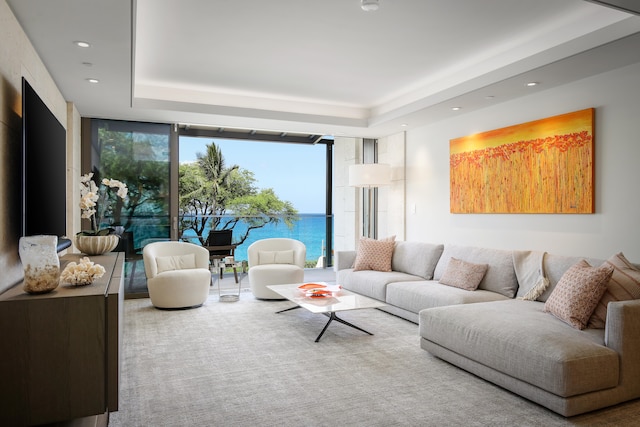 carpeted living room featuring a water view and a raised ceiling