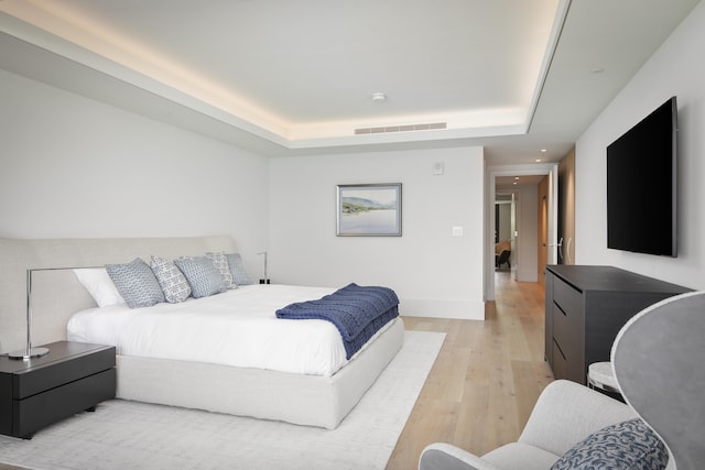 bedroom featuring a tray ceiling and light hardwood / wood-style flooring