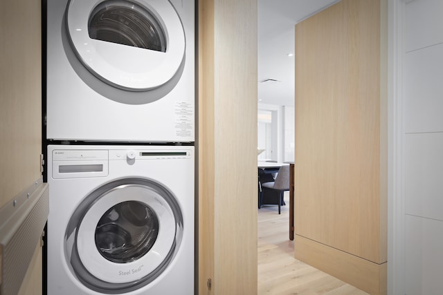 laundry room featuring light hardwood / wood-style floors and stacked washer / drying machine