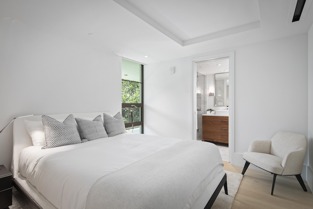 bedroom with connected bathroom and hardwood / wood-style floors