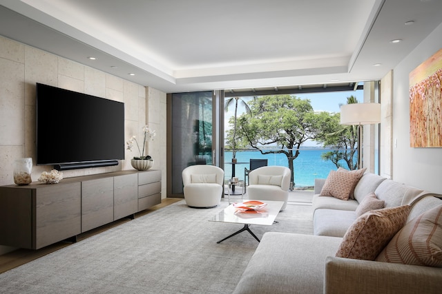 living room with a water view and a tray ceiling