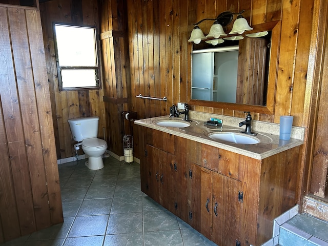 bathroom featuring tile patterned flooring, vanity, wood walls, and toilet