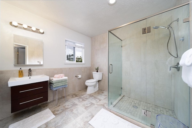 bathroom with vanity, toilet, a shower with door, and tile walls