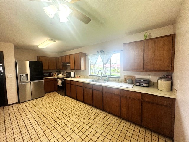 kitchen featuring appliances with stainless steel finishes, sink, light tile patterned floors, and ceiling fan