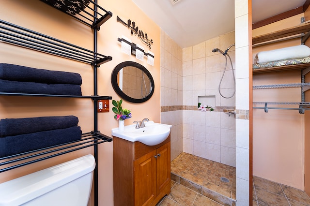 bathroom with toilet, vanity, and a tile shower