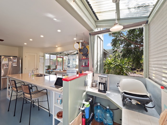 kitchen featuring a breakfast bar area, sink, and stainless steel fridge