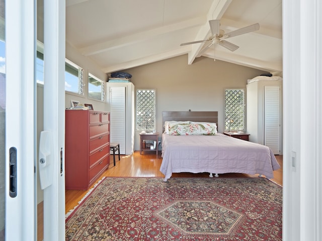 bedroom with ceiling fan, hardwood / wood-style flooring, and vaulted ceiling with beams