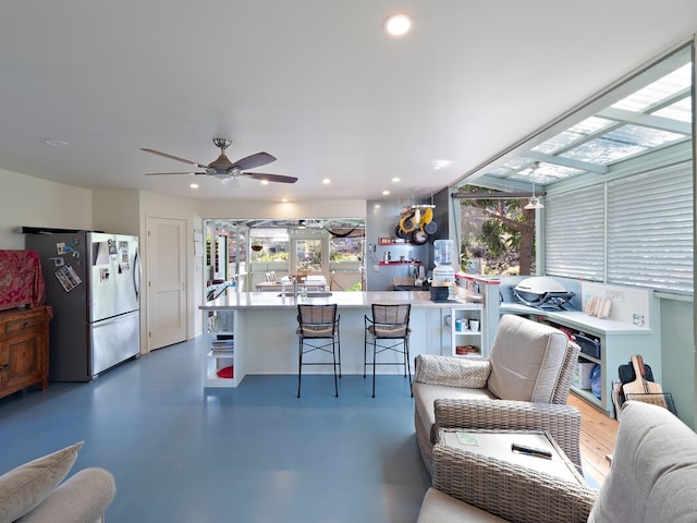 living room featuring ceiling fan and concrete flooring