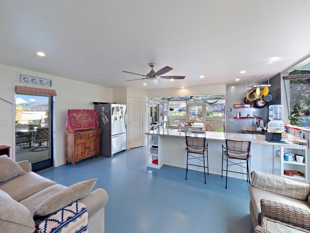 kitchen with stainless steel fridge, ceiling fan, and a breakfast bar