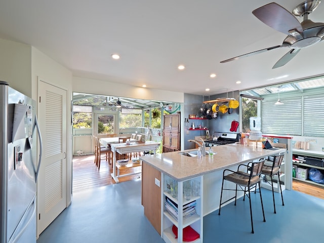 kitchen with dark wood-type flooring, a center island with sink, sink, light stone countertops, and white refrigerator