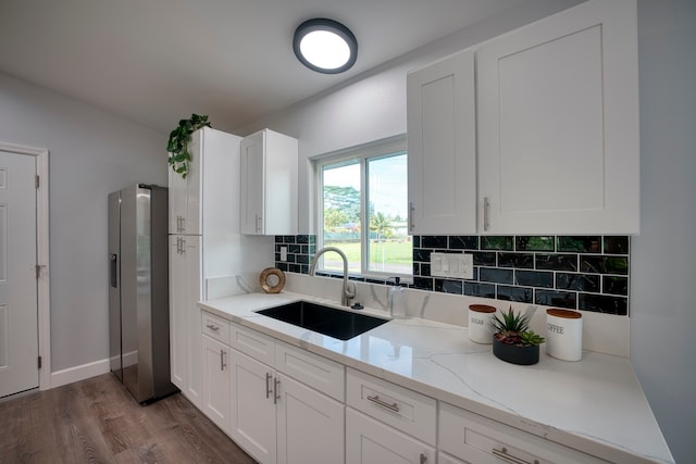 kitchen with sink, stainless steel refrigerator with ice dispenser, light stone countertops, dark hardwood / wood-style flooring, and white cabinetry