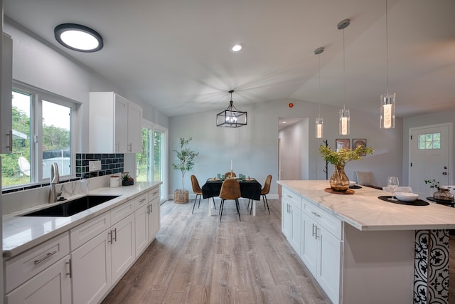 kitchen featuring backsplash, sink, pendant lighting, white cabinetry, and lofted ceiling