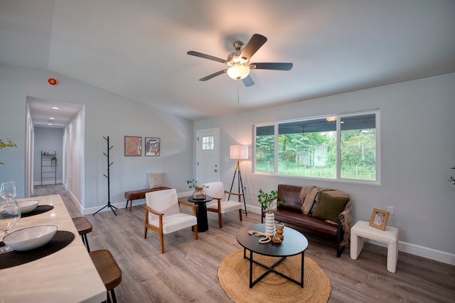 living room with ceiling fan, light hardwood / wood-style flooring, and vaulted ceiling