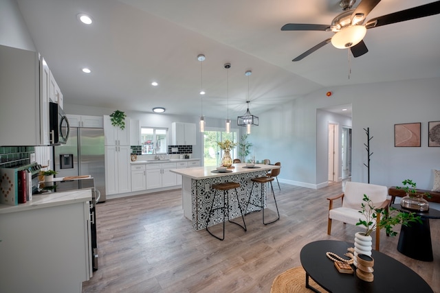 kitchen with sink, light hardwood / wood-style flooring, decorative light fixtures, a kitchen island, and white cabinetry