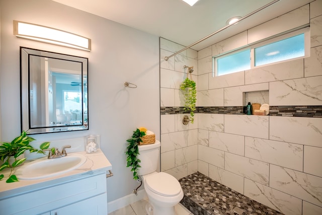 bathroom featuring a tile shower, vanity, and toilet