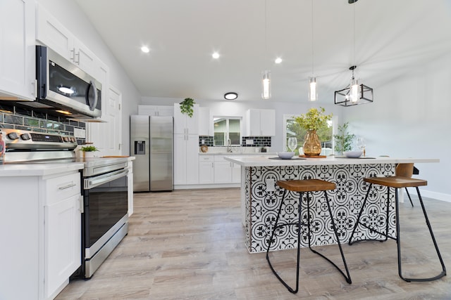 kitchen with white cabinets, decorative light fixtures, stainless steel appliances, and tasteful backsplash