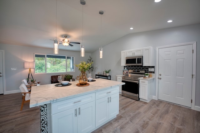 kitchen with white cabinets, appliances with stainless steel finishes, light hardwood / wood-style flooring, and a kitchen island