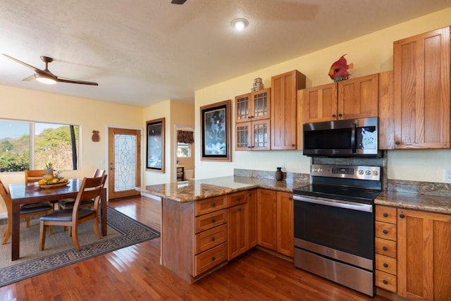 kitchen featuring kitchen peninsula, dark hardwood / wood-style flooring, stainless steel appliances, and a textured ceiling