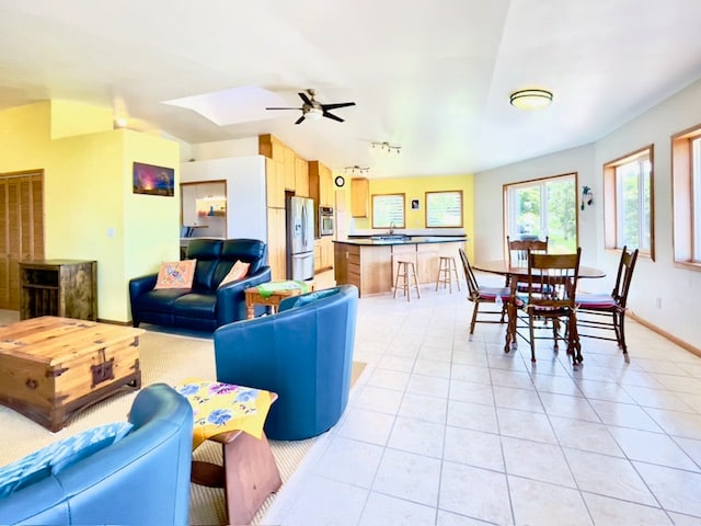 tiled living room with ceiling fan and sink