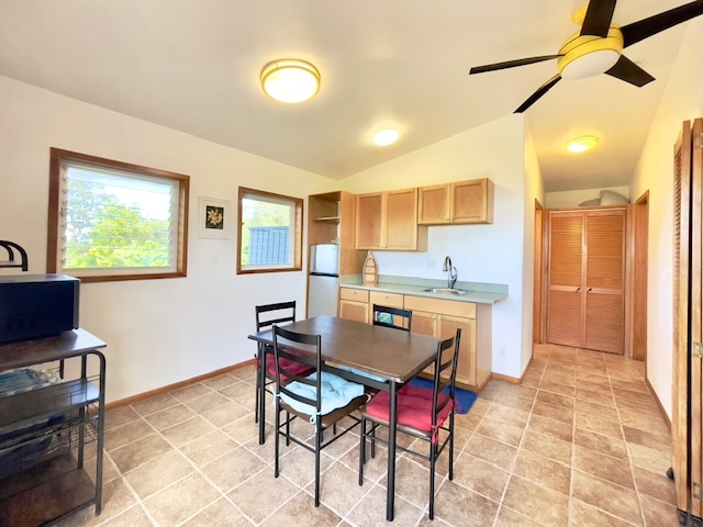 kitchen featuring light brown cabinetry, ceiling fan, sink, white refrigerator, and lofted ceiling