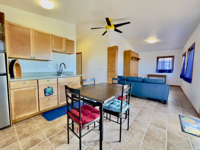 tiled dining room featuring ceiling fan, sink, and lofted ceiling