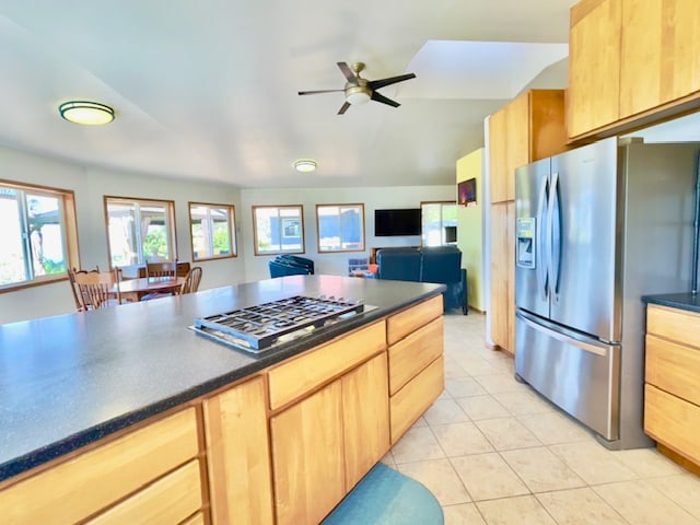 kitchen featuring ceiling fan, stainless steel appliances, vaulted ceiling, light brown cabinetry, and light tile patterned flooring