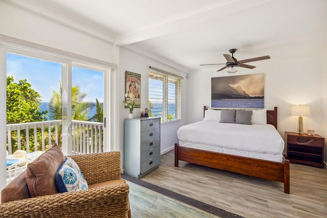 bedroom featuring light hardwood / wood-style flooring, multiple windows, a water view, and ceiling fan