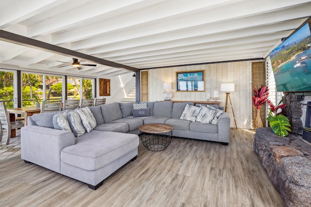 living room with beam ceiling, hardwood / wood-style flooring, ceiling fan, and wooden walls