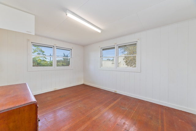 empty room with dark hardwood / wood-style floors and wooden walls