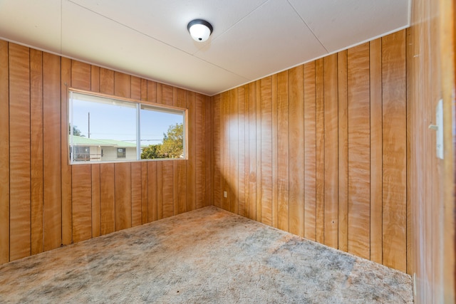 carpeted spare room with wooden walls