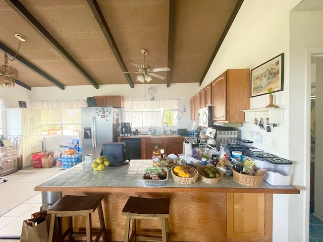 kitchen featuring tile countertops, lofted ceiling with beams, appliances with stainless steel finishes, and a wealth of natural light