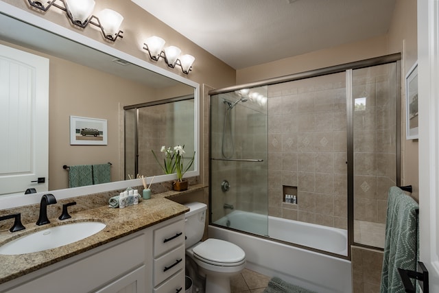 full bathroom featuring tile patterned flooring, enclosed tub / shower combo, a textured ceiling, toilet, and vanity