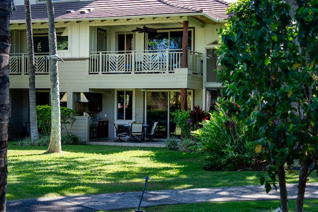 rear view of property with a yard, a balcony, ceiling fan, and a patio area