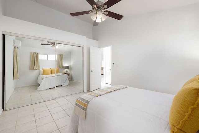 bedroom with ceiling fan, a closet, light tile patterned floors, and a wall mounted air conditioner