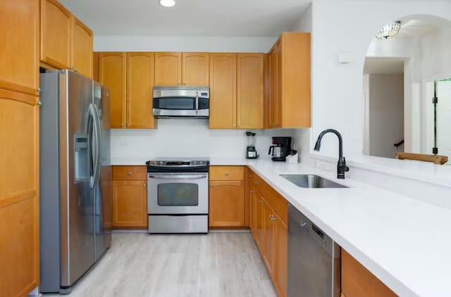 kitchen with light hardwood / wood-style floors, stainless steel appliances, and sink