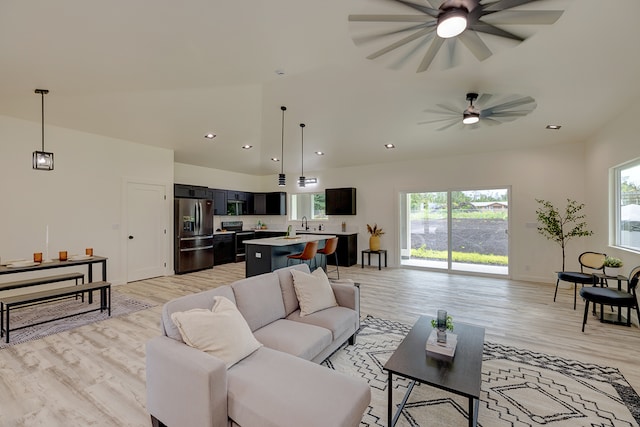 living room with plenty of natural light, ceiling fan, lofted ceiling, and light hardwood / wood-style flooring