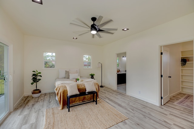 bedroom featuring access to outside, ceiling fan, a spacious closet, light wood-type flooring, and connected bathroom